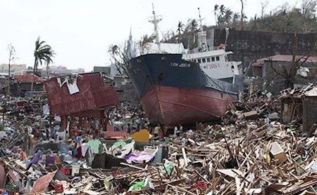 Super typhoon Haiyan: survivors walk past a ship that lies on top of damaged homes