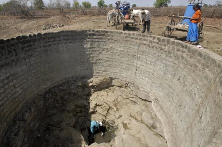 Villagers collect water from a nearly dry well at Jainoor village